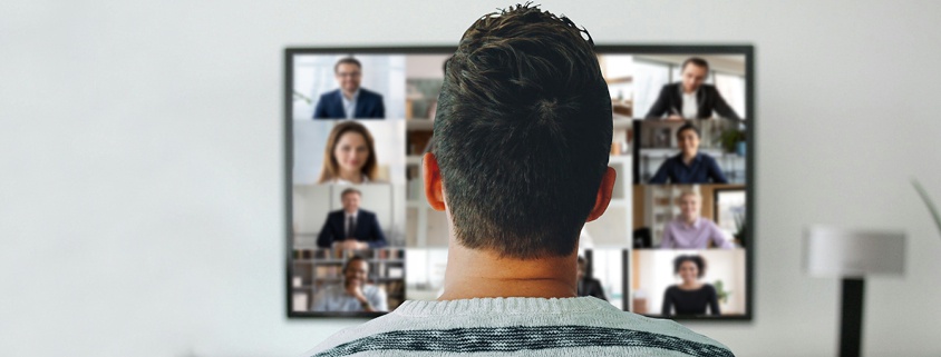 Symbolbild Video: Mann sitzt vor Fernseher und hat eine Videokonferenz